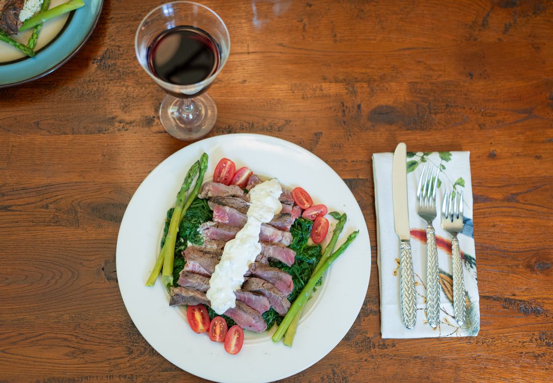 Grilled and blackened strip steak on a bed of spinach topped with blue cheese dressing